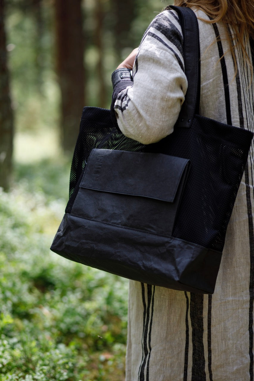 Black kraftex bag on womans shoulder with Fiilii logo. 